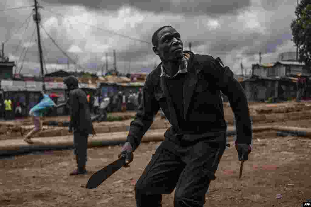 A protester brandishing a machete and a knife prepares to take cover from incoming tear gas canisters during clashes with police forces in Kibera, Nairobi. Kenyans trickled into polling stations for a repeat election that has polarized the nation, amid sporadic clashes as supporters of opposition leader ignored his call to stay away and tried to block voting.