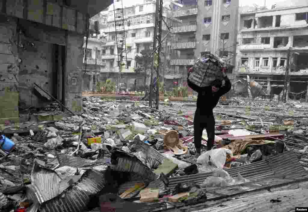 A man carries a bag amid damage and debris in the besieged area of Homs, Jan. 26, 2014. 