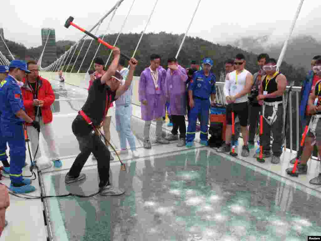 A man strikes a hammer against a 430-meter-long glass-bottom bridge during a safety test ceremony in Zhangjiajie, Hunan province, China, June 25, 2016.