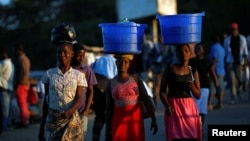 FILE - Women carry baskets with food items on their heads at a market in Blantyre, Malawi, July 10, 2017.