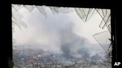 une fenêtre brisée par les ondes de choc encadrent le site d'une explosion dans un entrepôt dans la municipalité de Tianjin au nord-est de la Chine , le 14 Août 2015.