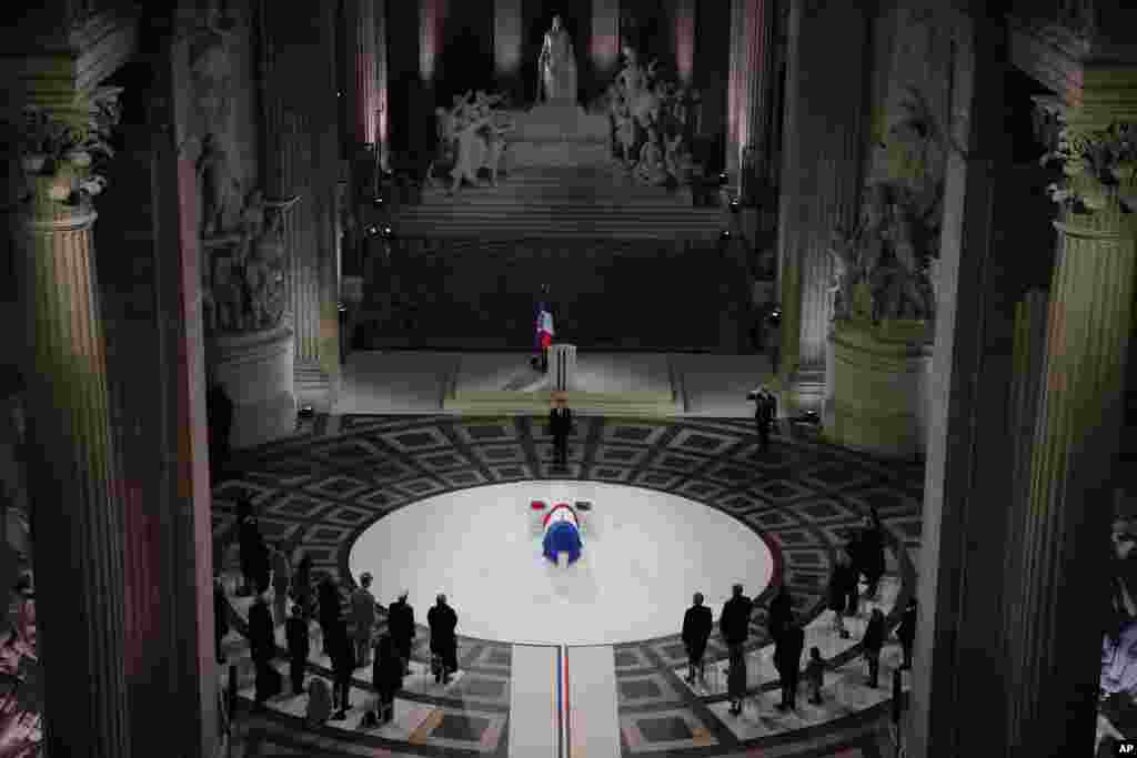 French President Emmanuel Macron stands by the coffin of World War I fighter Maurice Genevoix inside the Pantheon monument in Paris.