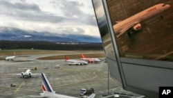 FILE - A passenger plane is reflected in a window of the airport tower as it arrives in Geneva, Switzerland.