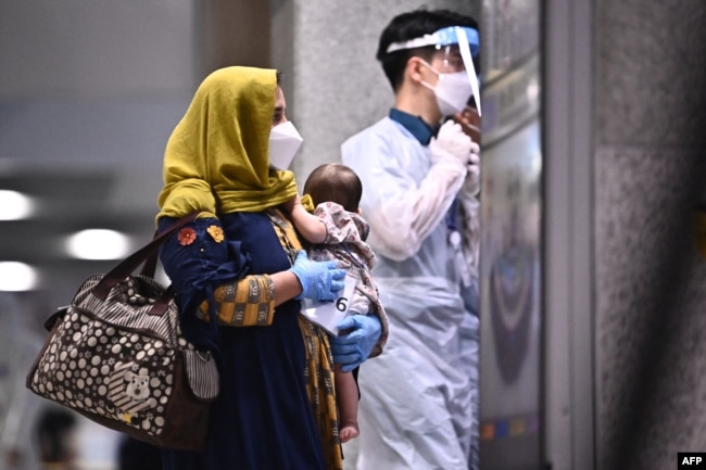 Pengungsi Afghanistan tiba di Bandara Internasional Incheon di Incheon, 26 Agustus 2021, setelah melarikan diri dari negara mereka menyusul pengambilalihan militer Taliban atas Afghanistan. (Anthony WALLACE / AFP)