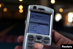 A man scrolls through his mobile phone to carry out a money transaction via M-PESA in Nairobi, Kenya in this May 12, 2009 photo.