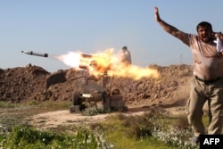 FILE - A fighter from the pro-government Popular Mobilisation (Hashd al-Shaabi) units covers his ears as he sets off a rocket launcher in the village of Taz Khurmatu, on the southern outskirts of the northern Iraqi city of Kirkuk, as they try to recpature the nearby village of al-Bashir from Islamic State (IS) group jihadists on February 16, 2016.