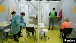 Yaşlılar, Almanya'nın Berlin kentindeki fuar merkezi Messe Berlin'de kurulan Corona virüsü aşı merkezinde aşılanıyor.