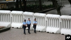 Police officers patrol in front of crowd-control barriers near the hotel where top Chinese official, Zhang Dejiang, will stay during his three-day visit to Hong Kong, May 17, 2016. The semiautonomous city has been the scene of rising discontent with Chinese rule.