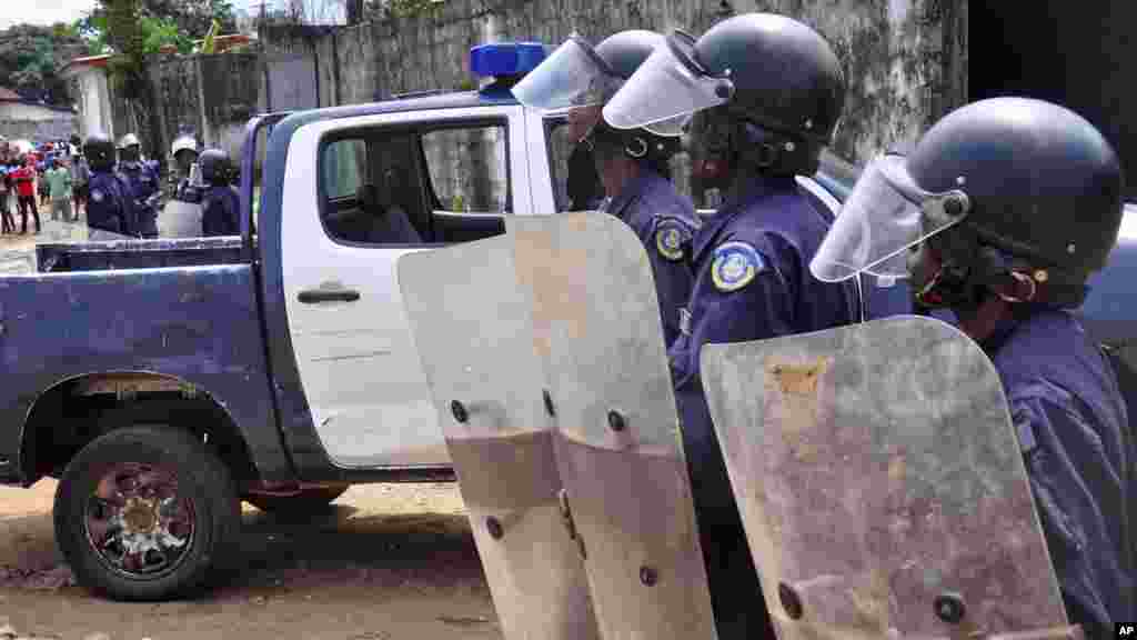 Liberian policemen dressed in riot gear disperse a crowd of people that blocked a main road after the body of someone suspected of dying from the Ebola virus was left in the street by health workers, Monrovia, Aug. 14, 2014.