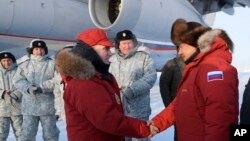 Russian President Vladimir Putin, center, shakes hands with Defense Minister Sergei Shoigu as he visits Franz Josef Land archipelago in the Arctic, Russia, March 29, 2017.
