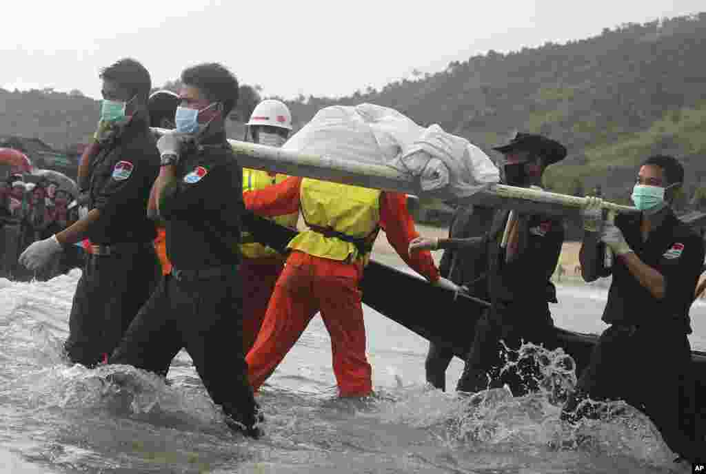 Rescue personnel carry bodies recovered by fishing vessels in the waters off San Hlan village, in Laung Lone township, southern Myanmar. Fishermen have joined navy and air force personnel in recovering bodies and aircraft parts from the sea off Myanmar, where a military plane carrying 122 people including 15 children crashed a day earlier.