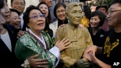 Former World War II "comfort woman" Yongsoo Lee, 89, of South Korea, stands by a statue of Haksoon Kim while looking at the "Comfort Women" monument after it was unveiled, Sept. 22, 2017, in San Francisco. 