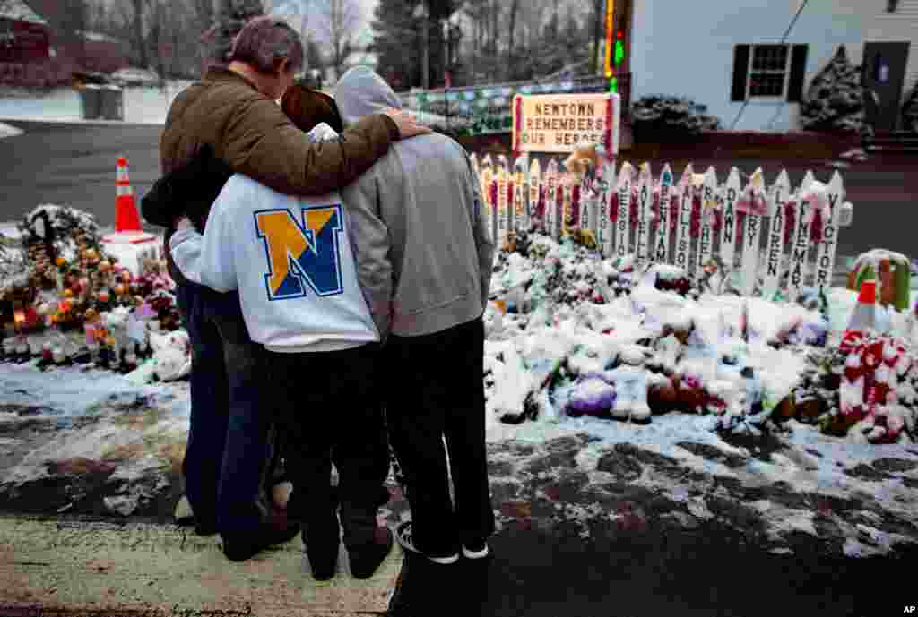 Members of the Rutter family embrace early Christmas morning as they stand near memorials by the Sandy Hook firehouse in Newtown, Connecticut, December 25, 2012.