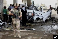 Pasukan keamanan Irak dan warga setempat melihat lokasi serangan bom mobil di distrik Husseiniyah, pinggiran Baghdad, Senin (6/5).