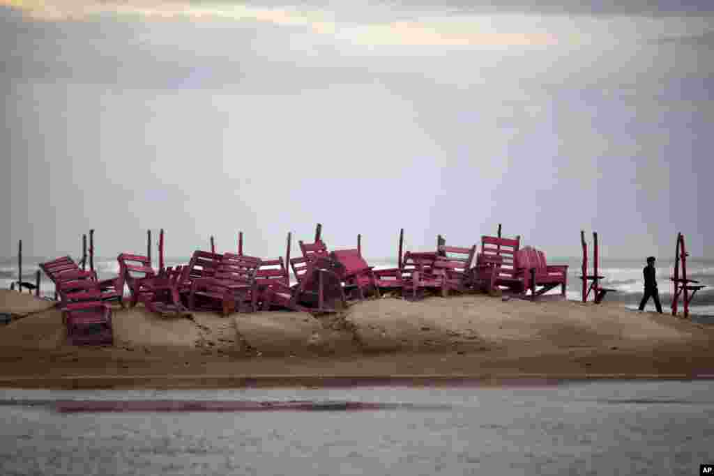 A man walks past tied up chairs at the Miramar beach as Hurricane Ingrid approaches the coast in Ciudad Madero, Mexico, Sept. 15, 2013.&nbsp;