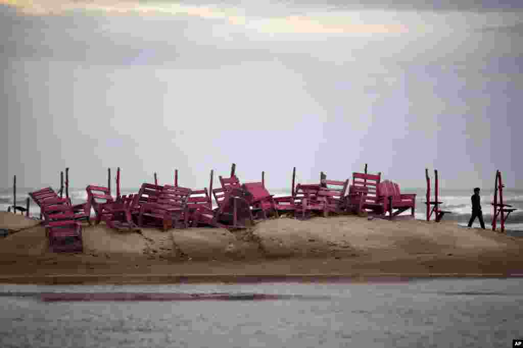 A man walks past tied up chairs at the Miramar beach as Hurricane Ingrid approaches the coast in Ciudad Madero, Mexico, Sept. 15, 2013. 