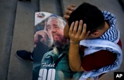Palestinian medical student Adham Motawi, with an image of Fidel Castro, holds his head in disbelief during a gathering in Castro's honor in Havana, Cuba, the day after his death, Nov. 26, 2016.