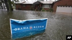 A campaign sign rises above floodwaters as rain continues falling in Norfolk, VA, Oct. 29, 2012.