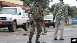 FILE - A Burundian soldier with his gun and rocket launcher guard a deserted street in Bujumbura, Burundi.