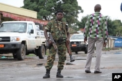 FILE - A Burundian soldier with his gun and rocket launcher guard a deserted street in Bujumbura, Burundi.
