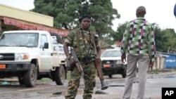 FILE - A Burundian soldier, with gun and rocket launcher, patrols a street in Bujumbura, Burundi.