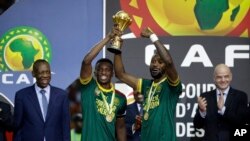 Les Camerounais Benjamin Moukandjo, à gauche, et Nicolas Nkoulou avec le trophée de la CAN 2017, à Libreville, au Gabon, le 5 février 2017.