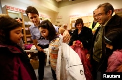 Canada's Prime Minister Justin Trudeau helps a young Syrian refugee try on a winter coat after she arrived with her family from Beirut at the Toronto Pearson International Airport in Mississauga, Ontario, Canada, Dec. 11, 2015.