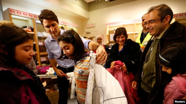 El primer ministro de Canadá, Justin Trudeau, ayuda a una joven refugiada siria a probarse un abrigo. La niña llegó con su familia procedente de Beirut, con el primer grupo de refugiados sirios que llegó a Canadá en un avión militar, en 2015.