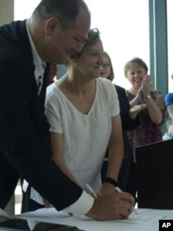 Dominic Smart, general manager of the Millennium Hotel, and Carol Smolenski, executive director of ECPAT USA, sign the anti-sex trafficking pledge.