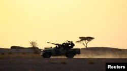 Les soldats du Front Polisario conduisent une camionnette surmontée d'une arme anti-aérienne pendant le coucher du soleil à Bir Lahlou, Sahara Occidental, le 9 septembre 2016.