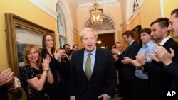 Perdana Menteri Boris Johnson disambut oleh anggota stafnya saat tiba di kantor perdana menteri, 10 Downing Street, London, setelah bertemu Ratu Elizabeth, 13 Desember 2019. 