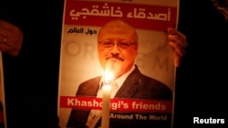 FILE - A protester holds a poster with a picture of slain Saudi journalist Jamal Khashoggi, outside Saudi Arabia's consulate in Istanbul, Turkey, Oct. 25, 2018.