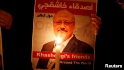 FILE - A protester holds a poster with a picture of slain Saudi journalist Jamal Khashoggi, outside Saudi Arabia's consulate in Istanbul, Turkey, Oct. 25, 2018.