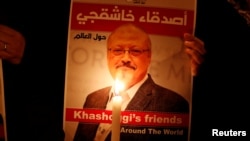 Seorang demonstran di luar konsulat Arab Saudi di Istanbul, Turki, 25 Oktober 2018, menyuarakan protes sambil memegang poster jurnalis Saudi yang tewas dibunuh, Jamal Khashoggi.