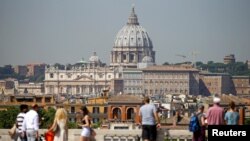 FILE - Tourists take pictures of Saint Peter's Basilica from Pincio terrace in downtown Rome, Italy, Aug. 3, 2017.