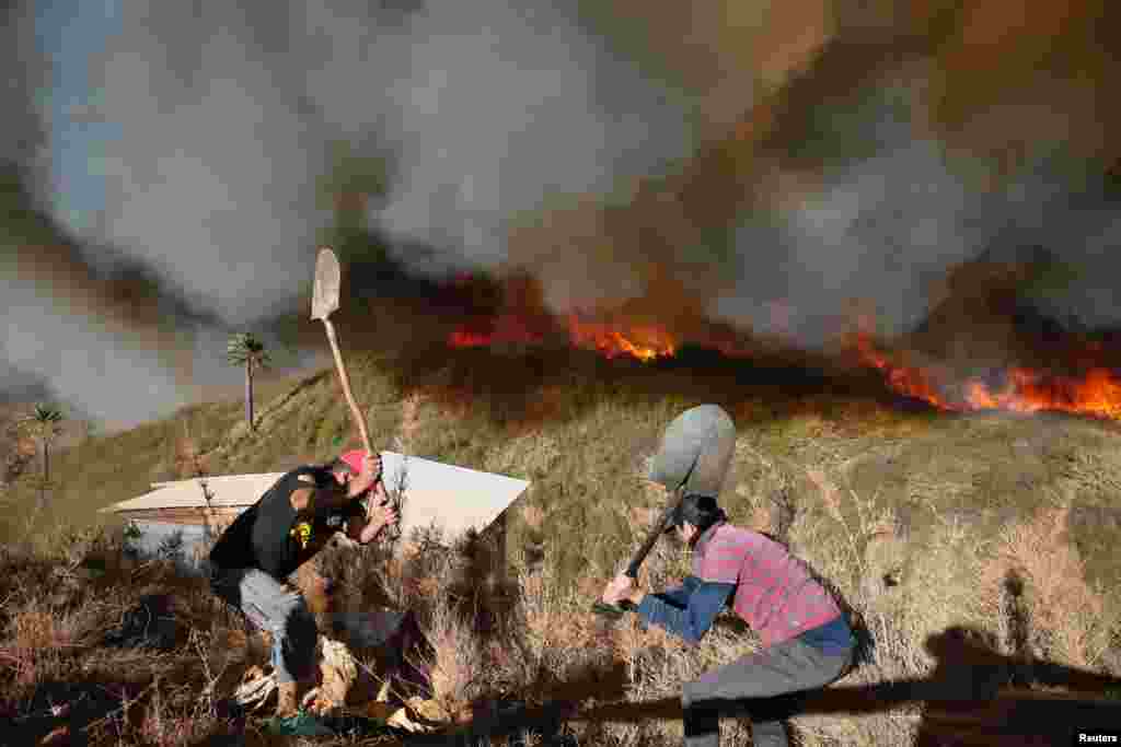 Residents work to prevent a wildfire from spreading to their homes in Vina del Mar, Chile, March 12, 2017.