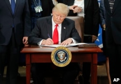 President Donald Trump signs an executive order for border security and immigration enforcement improvements at the Homeland Security Department in Washington, Jan. 25, 2017.