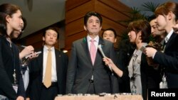 Japan's Prime Minister Shinzo Abe (C) speaks to media after a meeting with cabinet ministers at his official residence in Tokyo, in this photo taken by Kyodo, April 12, 2013.