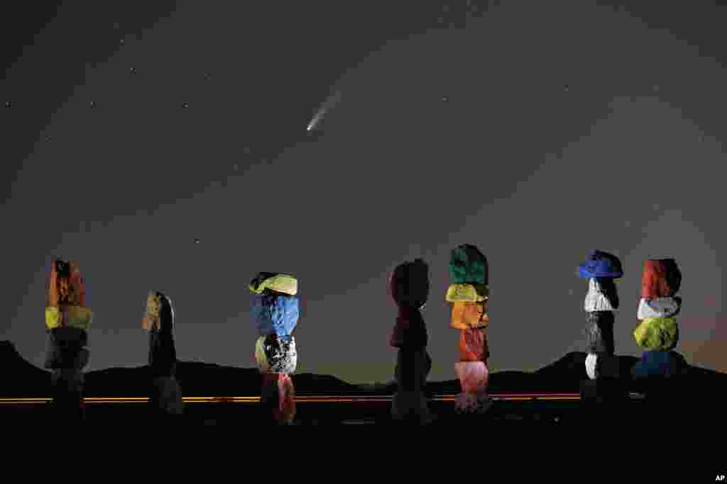 The comet Neowise, or C/2020 F3, is seen in the evening sky above the artwork titled: "Seven Magic Mountains" by artist Ugo Rondinone, Thursday, July 16, 2020, near Jean, Nev., south of Las Vegas. (AP Photo/John Locher)