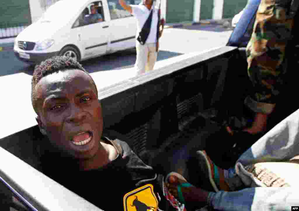 25 tháng 8: Một người bị tố giác là lính đánh thuê của Gadhafi bị bắt đưa lên xe của phe nổi dậy ở Tripoli. (REUTERS/Goran Tomasevic)