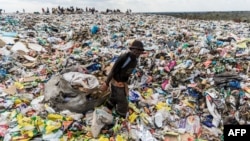 FILE - A recycler drags a huge bag of paper sorted for recycling past a heap of non-recyclable material at Richmond sanitary landfill site on 2 June 2018 in the industrial city of Bulawayo.