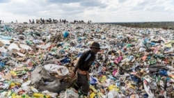 A recycler drags a huge bag of paper sorted for recycling past a heap of non-recyclable material at Richmond sanitary landfill site on 2 June 2018 in the industrial city of Bulawayo.