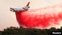A DC-10 air tanker drops fire retardant along the crest of a hill to protect the two bulldozers below that were cutting fire lines at the River Fire (Mendocino Complex) near Lakeport, Calif., Aug. 2, 2018.