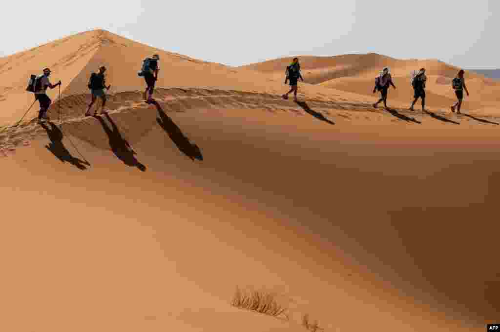 Pesaing mengambil bagian dalam Etape 3 dari Marathon des Sables ke-35 antara Kourci Dial Zaid dan Jebel El Mraier di gurun Sahara Maroko selatan pada 5 Oktober 2021. Lomba maraton ini menempuh jarak 250 kilometer melalui medan yang tangguh (sulit) di kawasan dengan iklim paling tidak bersahabat di dunia. (Foto: AFP)
