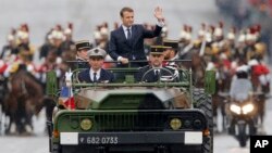 New French President Emmanuel Macron waves from a military vehicle as he rides on the Champs Elysees avenue towards the Arc de Triomphe in Paris, May 14, 2017. 