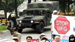U.S. Army vehicle passes by South Korean protesters at a rally denouncing a South Korea-U.S. Combined Forces Command military exercise, in Seongnam, south of Seoul, South Korea, August 16, 2011