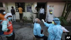 အိန္ဒိယနိုင်ငံ New Delhi မြို့မှာ COVID 19 ရှိမရှိ စစ်ဆေးဖို့ swab နမူနာ ယူနေတဲ့ ကျန်းမာရေးဝန်ထမ်းတဦး။