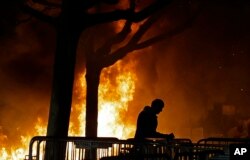 FILE - In this Feb. 1, 2017, photo, a fire set by demonstrators protesting a scheduled speaking appearance by Breitbart News editor Milo Yiannopoulos burns on Sproul Plaza on the University of California-Berkeley campus.