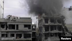 Smoke rises from a building after it was hit by what activists said was shelling by forces loyal to Syria's President Bashar al-Assad at the besieged area of Homs, Jan. 9, 2014. 