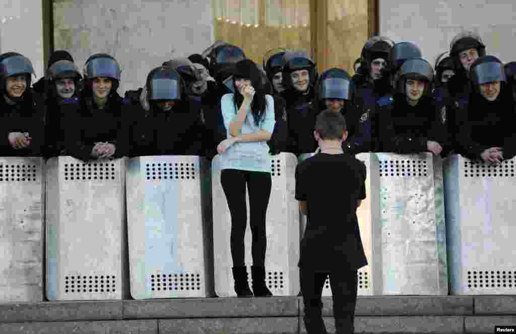 A man takes photos of his girlfriend next to Ukrainian riot police guarding the regional administration building following a pro-Russian rally in Donetsk, March 23, 2014.